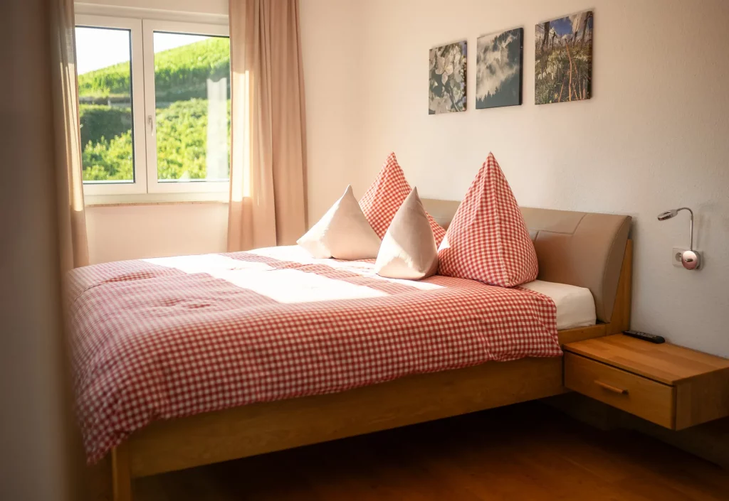 Gemütliches Doppelbett im Zimmer der Ferienwohnung Schlossblick in Kappelrodeck mit rot-weiß karierter Bettwäsche