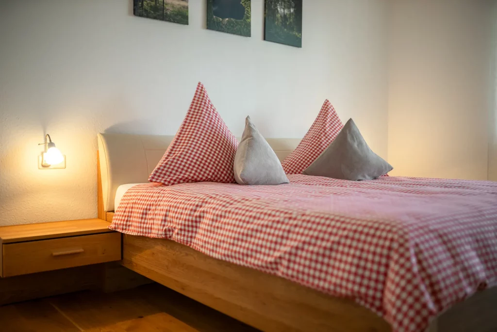 ferienwohnung-kappelrodeck-bassler-2000px-54 Gemütliches Doppelbett im Zimmer der Ferienwohnung Schlossblick in Kappelrodeck mit rot-weiß karierter Bettwäsche